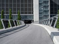 a small concrete walkway near a large glass building with a metal frame over it in front