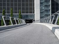 a small concrete walkway near a large glass building with a metal frame over it in front