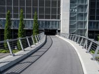 a small concrete walkway near a large glass building with a metal frame over it in front