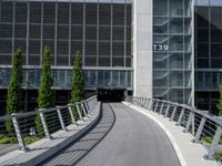 a small concrete walkway near a large glass building with a metal frame over it in front