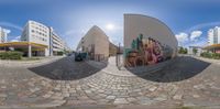 a photograph taken from a fisheye lens with a street below, with buildings, and a bus,