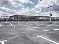 parking lot with clouds overhead and a pedestrian crossing sign to the left of it, next to an overhang