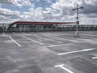 parking lot with clouds overhead and a pedestrian crossing sign to the left of it, next to an overhang