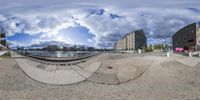 some clouds and buildings are in a photo with a fish eye lens that shows a small part of the city in the middle of them