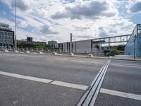 a freeway bridge with traffic passing on the opposite side and buildings in the background with clouds