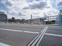 a freeway bridge with traffic passing on the opposite side and buildings in the background with clouds