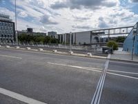 a freeway bridge with traffic passing on the opposite side and buildings in the background with clouds