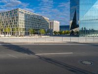 an empty city street with many large buildings in the background, including a large circular glass structure