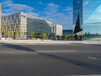 an empty city street with many large buildings in the background, including a large circular glass structure