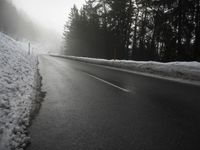 a cold, foggy road on a gloom morning in wintertime with a single skiboard