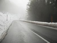 a cold, foggy road on a gloom morning in wintertime with a single skiboard