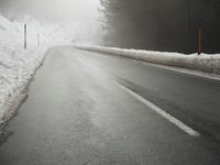 a cold, foggy road on a gloom morning in wintertime with a single skiboard