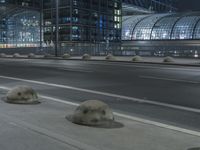 the empty city road is empty by the tall building in the background at night with light streaking on the buildings