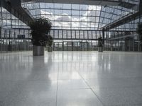 large glass atrium with potted plants on both sides and floor leveling the room