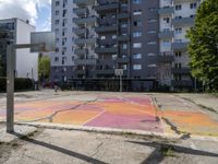 an empty basketball court is painted on a city street in bright colors with graffiti on the ground and walls