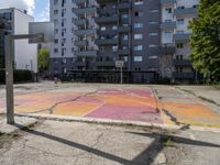 an empty basketball court is painted on a city street in bright colors with graffiti on the ground and walls