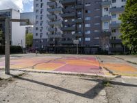 an empty basketball court is painted on a city street in bright colors with graffiti on the ground and walls