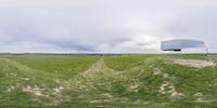 a grassy hill with a curved building in the middle of it at a grassy hilltop