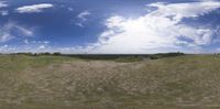 the view of clouds is reflected in a fisheye lens on the mirror in this landscape