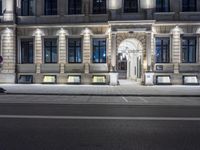 a street light is in front of a building at night, with lots of windows