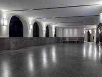 a hallway with an empty concrete floor and many lamps on the wall above them to illuminate