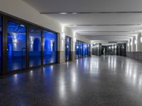 a long hallway with doors and a black floor in a building with light blue walls