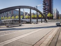 a walkway on the left side of a bridge and buildings in the background with light shining in the middle