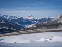 skiers stand on the side of the mountain and look over a beautiful view of snowy peaks