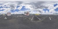 a fish eye lens view of the sky and clouds above a parking lot with cars