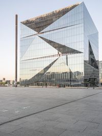 the exterior of a large building with lots of glass on top of it and people walking about it