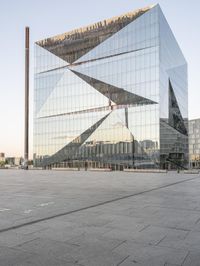 the exterior of a large building with lots of glass on top of it and people walking about it