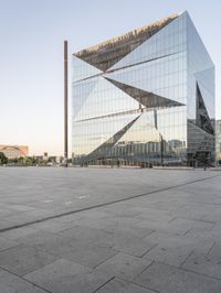 the exterior of a large building with lots of glass on top of it and people walking about it