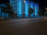 blue lights that are on the side of a road near a building at night time