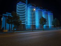 blue lights that are on the side of a road near a building at night time