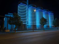 blue lights that are on the side of a road near a building at night time