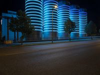 blue lights that are on the side of a road near a building at night time