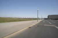 a white truck driving down the highway beside an empty parking lot below an overpass