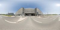 a large building sits near an empty highway and traffic lights, and two curved streets in front of it