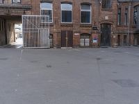 a very empty courtyard with a gate and street sign in front of it on the building