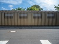 a metal building with a corrugated door in front of it and trees lining the street behind it