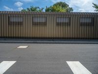 a metal building with a corrugated door in front of it and trees lining the street behind it