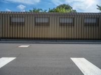 a metal building with a corrugated door in front of it and trees lining the street behind it