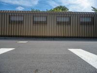 a metal building with a corrugated door in front of it and trees lining the street behind it