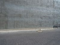 a bench and a cement wall near by the street corner on the sidewalk or on the sidewalk