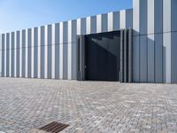 black door in front of a white wall with grey bricks on either side and a gray brick floor