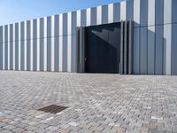 black door in front of a white wall with grey bricks on either side and a gray brick floor