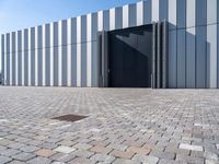 black door in front of a white wall with grey bricks on either side and a gray brick floor