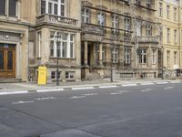 an empty building with signs on the street and people on bikes in traffic passing by