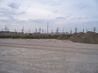 a view of a large amount of dirt in an empty field, with two trucks parked next to it