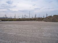 a view of a large amount of dirt in an empty field, with two trucks parked next to it